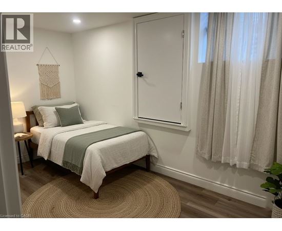 A bedroom with a bed, a nightstand, and a window with curtains.