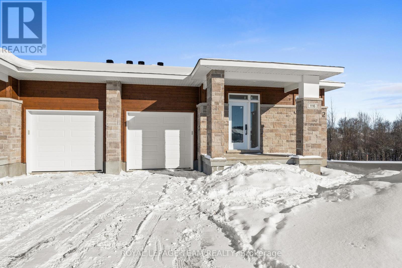 A house with a white garage door and a brown brick exterior is surrounded by snow.