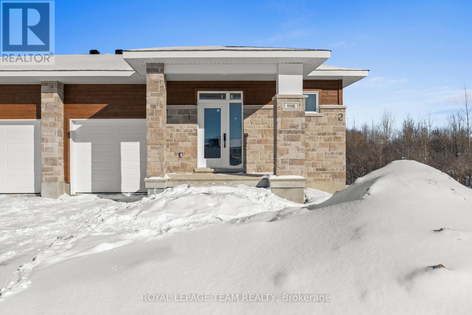 A house with a large mound of snow in front of it.