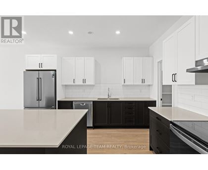 A kitchen with white cabinets and a black island.