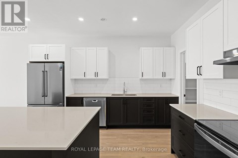 A kitchen with white cabinets and a black island.