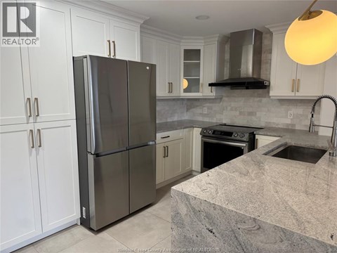 A kitchen with a refrigerator, sink, and stove.