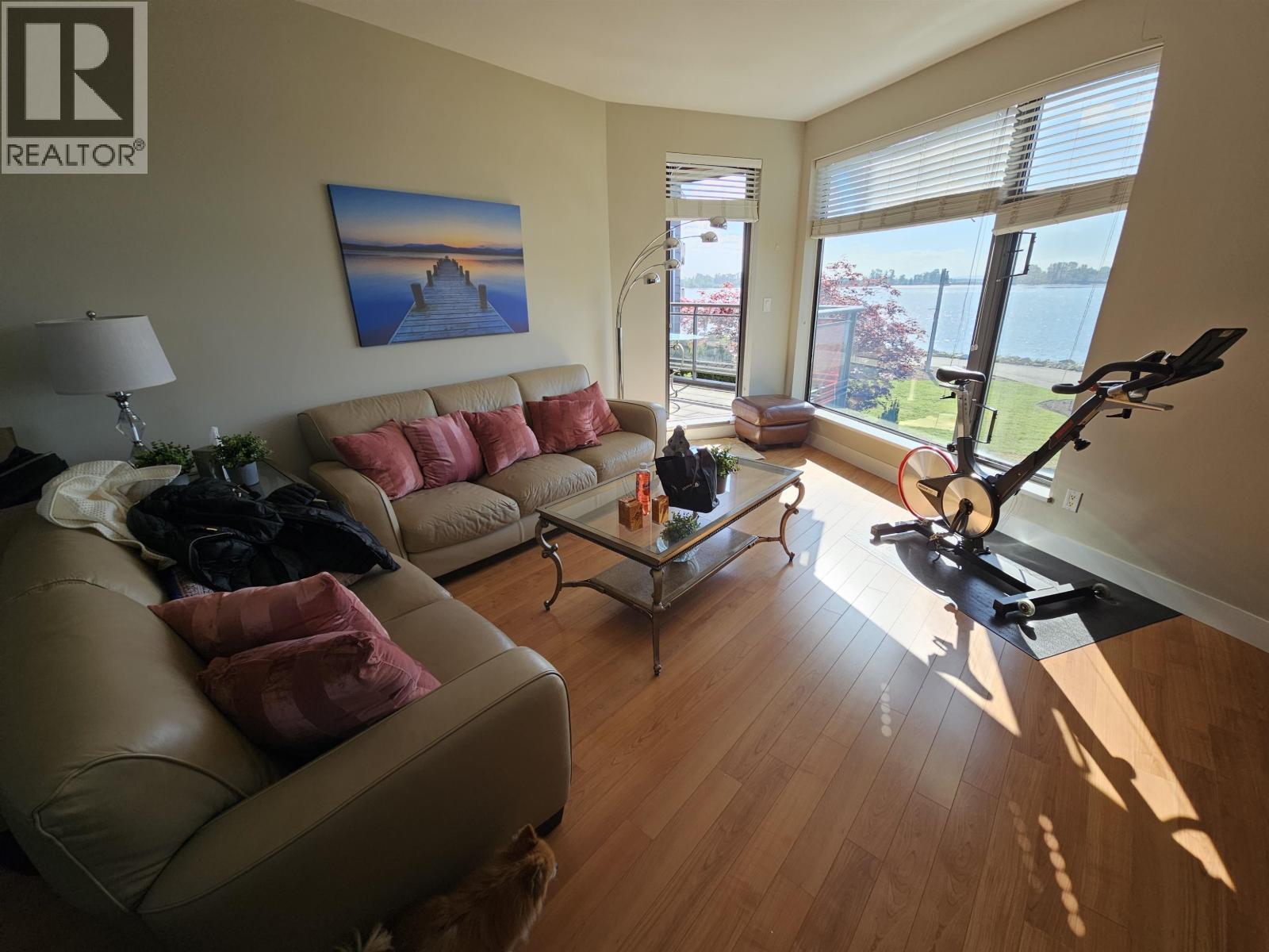A living room with a tan couch and a painting on the wall.