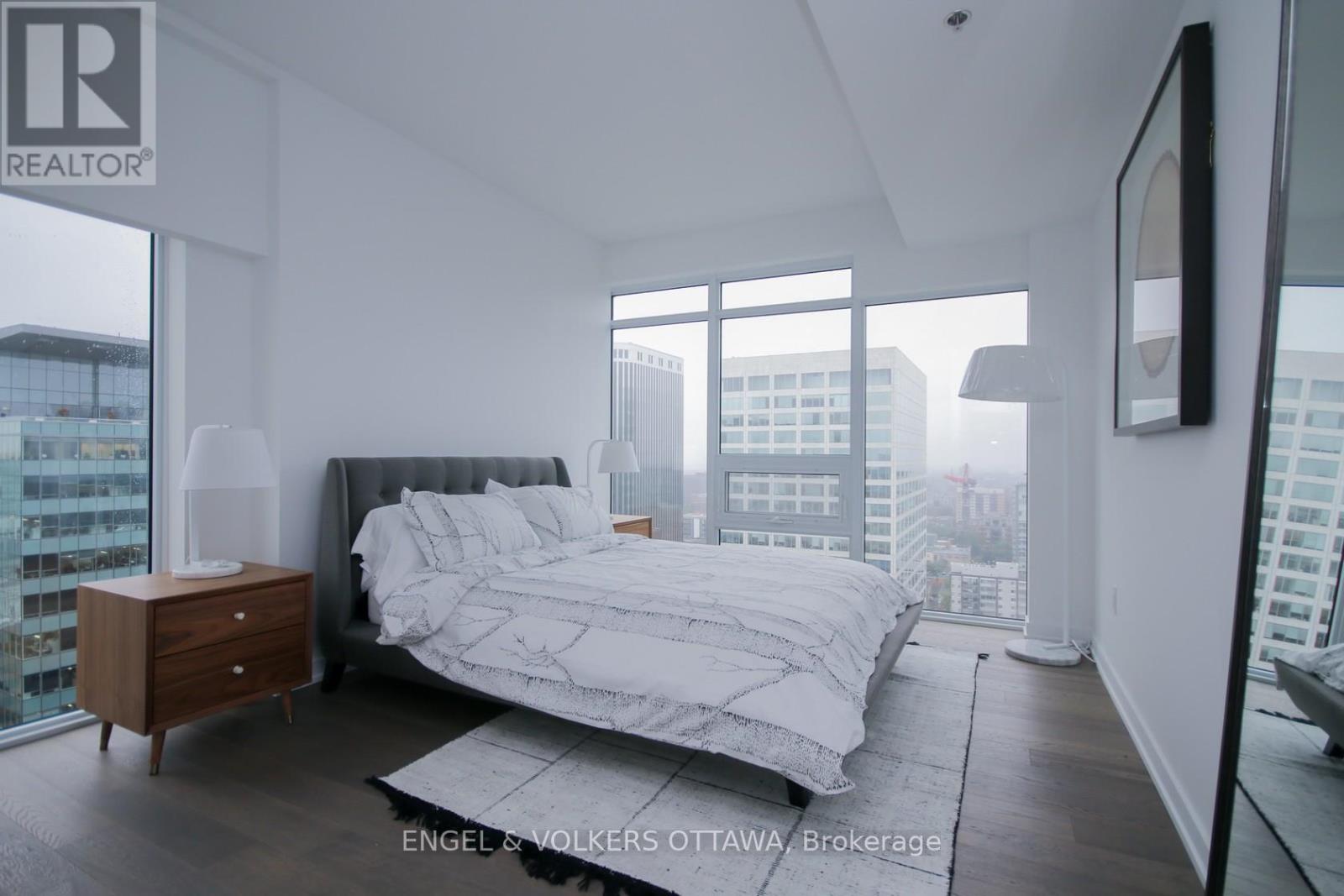 A bedroom with a large bed and a city view.