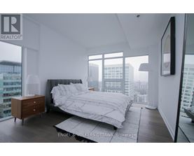 A bedroom with a large bed and a city view.