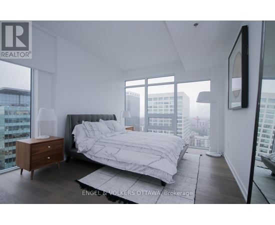 A bedroom with a large bed and a city view.