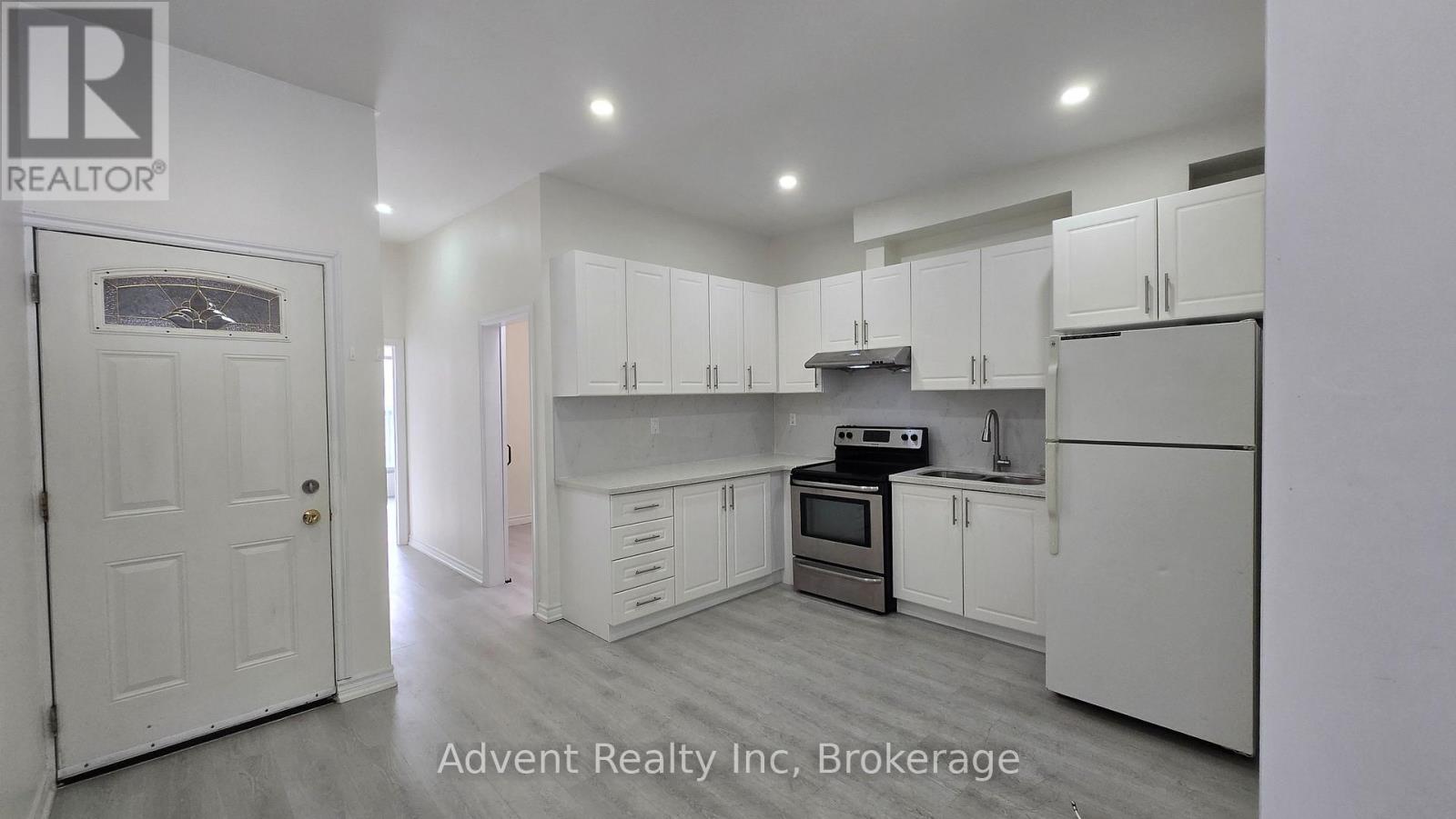 A white kitchen with a white door and white cabinets.