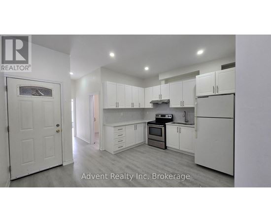 A white kitchen with a white door and white cabinets.