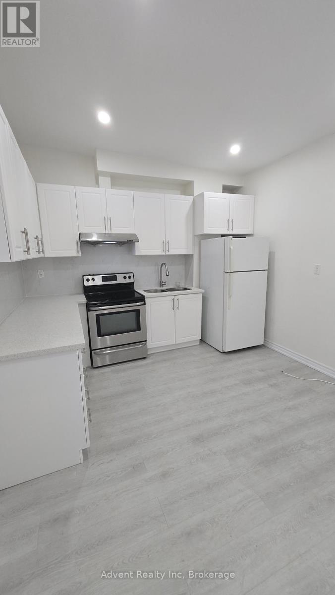 A white kitchen with a stove top oven and a refrigerator.