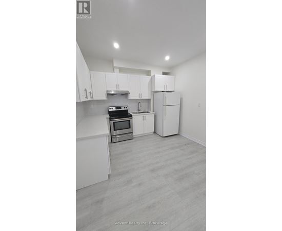 A white kitchen with a stove top oven and a refrigerator.