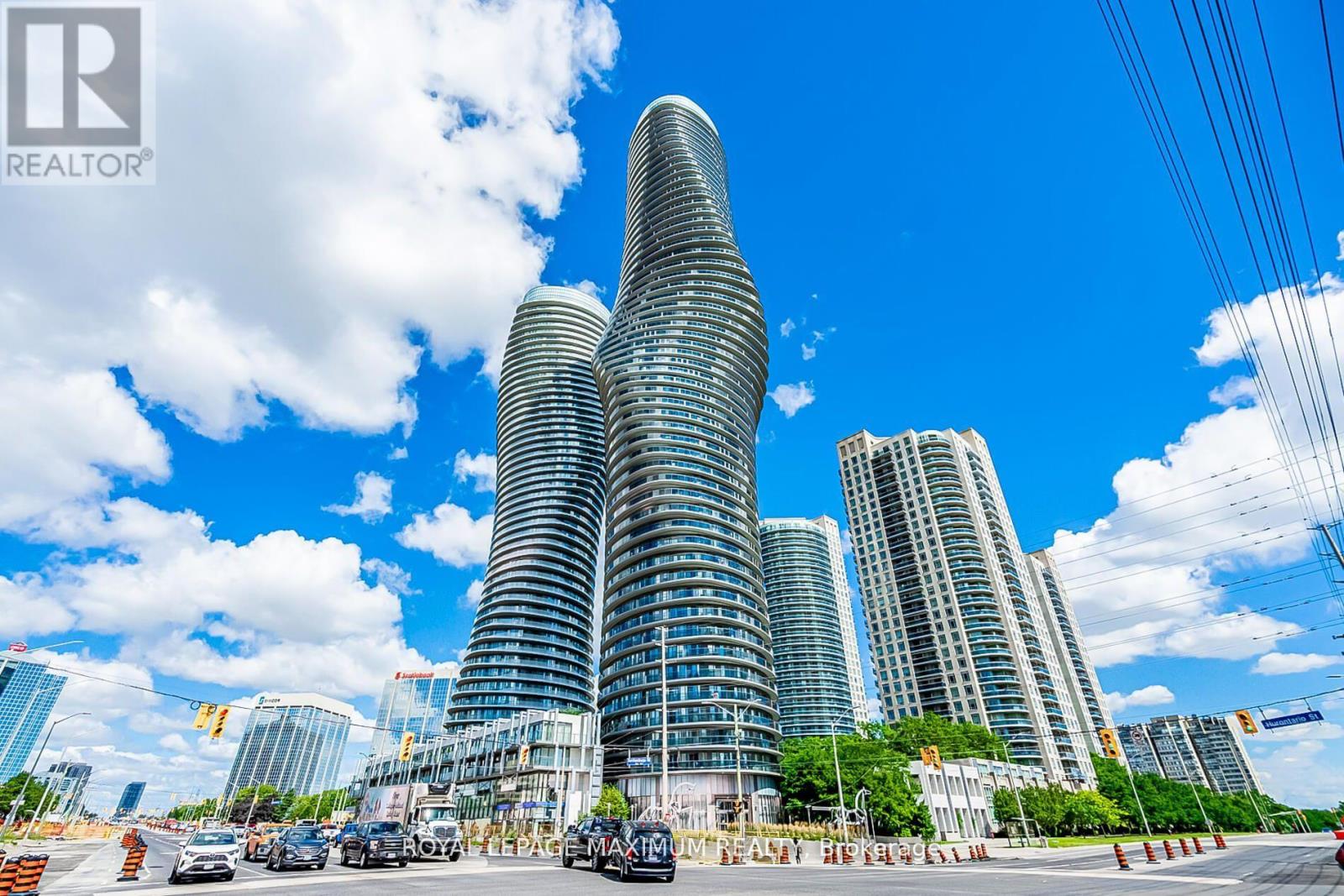 A cityscape with a tall building in the center and cars on the road.