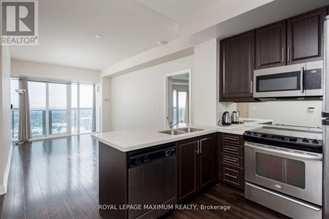 A modern kitchen with dark wood cabinets and stainless steel appliances.