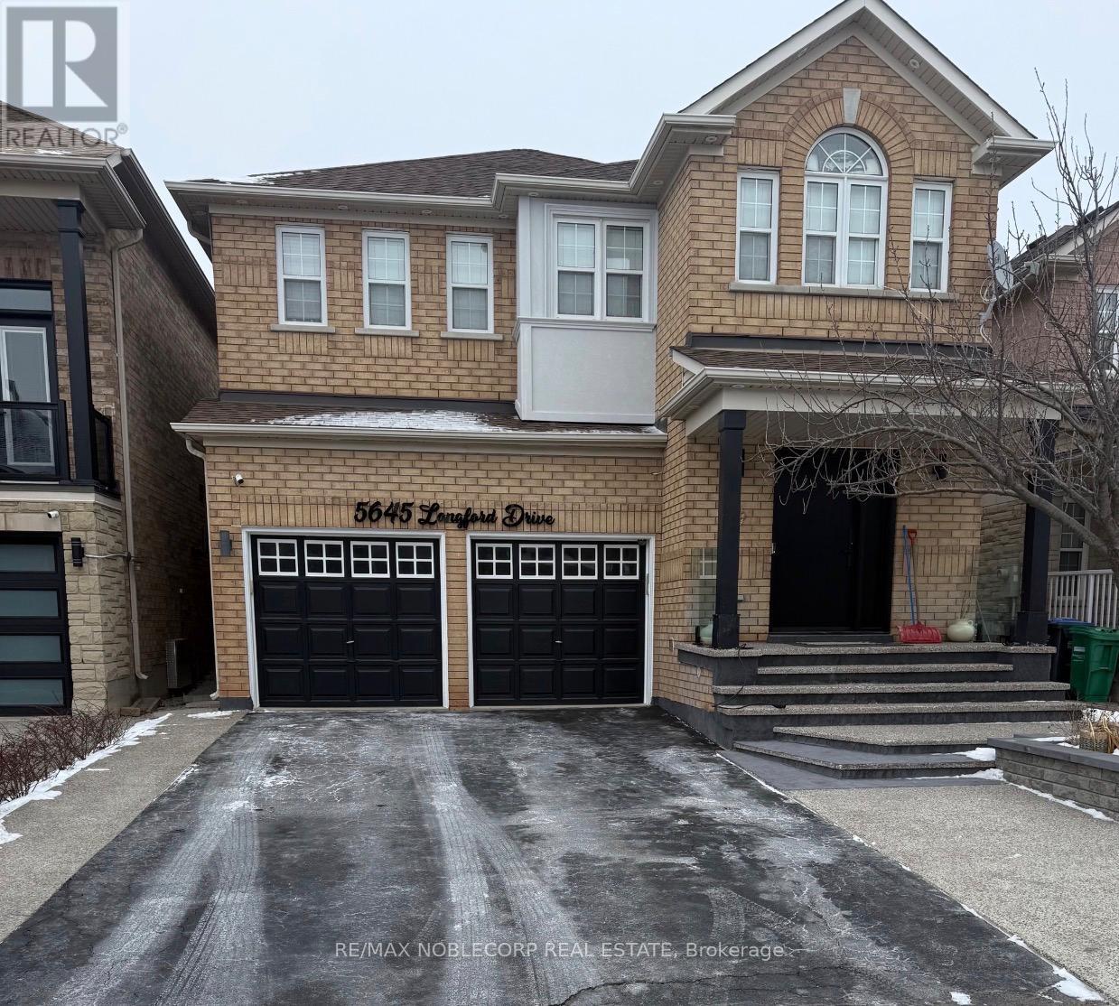A two-story brick house with a black garage door and a white door.