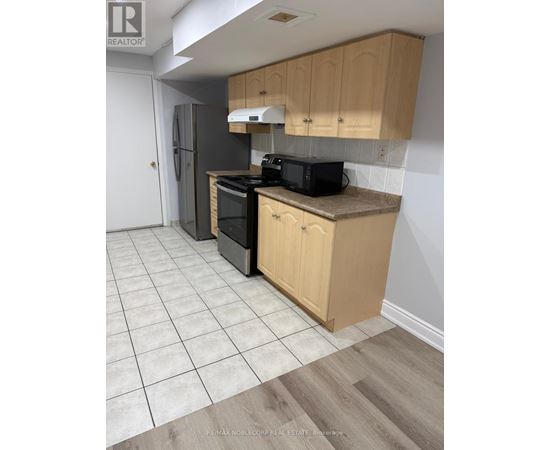 A kitchen with wooden cabinets and a black microwave.