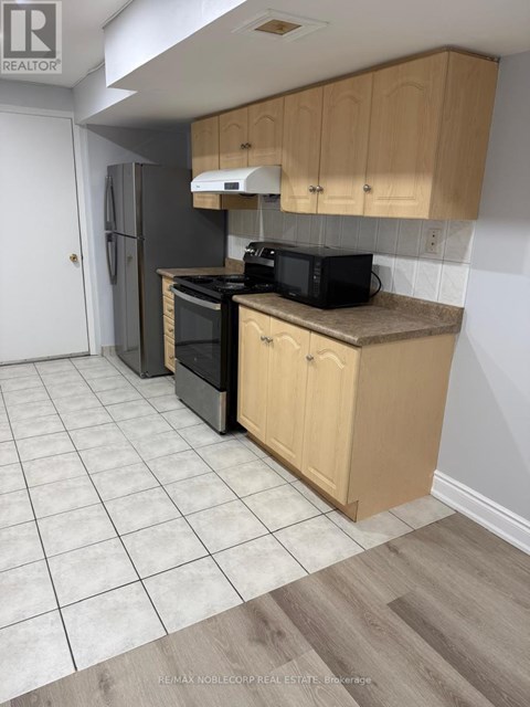 A kitchen with wooden cabinets and a black microwave.
