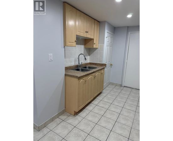 A kitchen with wooden cabinets and a tiled floor.