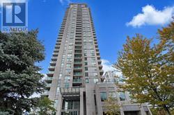 A tall residential building with balconies and a blue sky in the background.