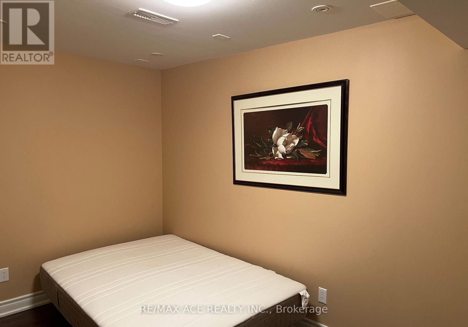 A bedroom with a bed and a framed picture on the wall.