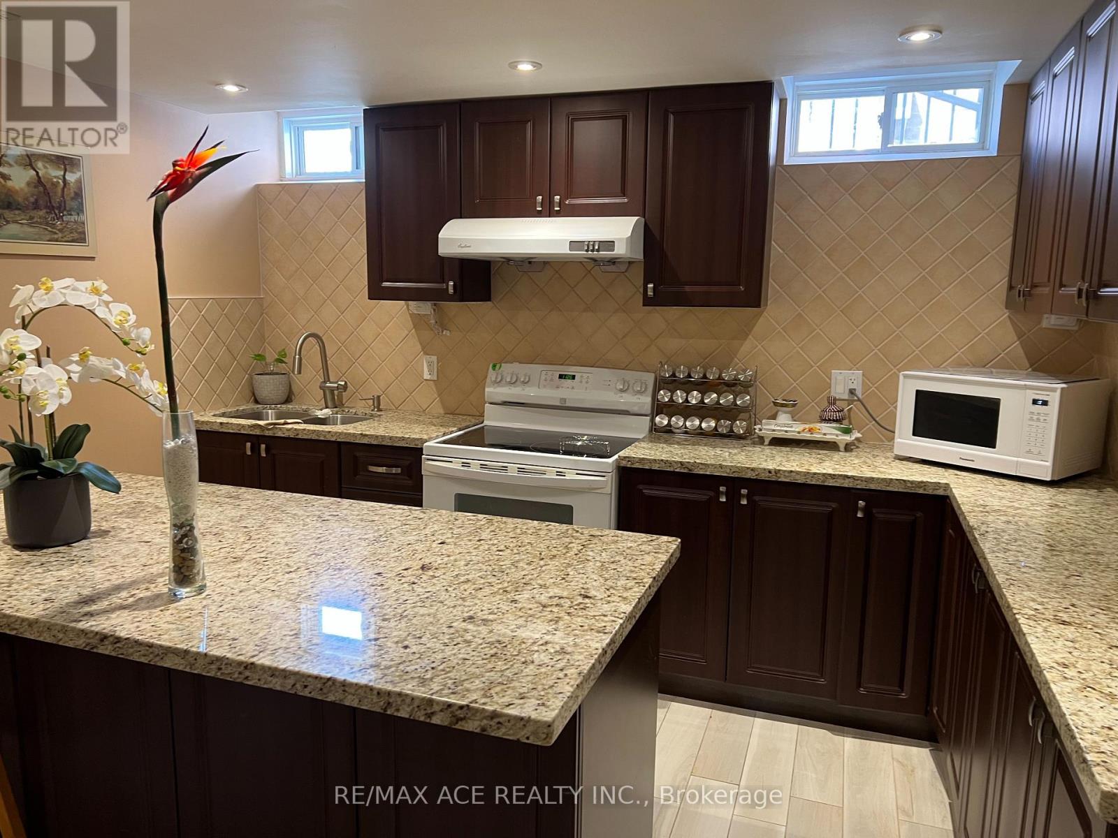A kitchen with granite countertops and dark brown cabinets.