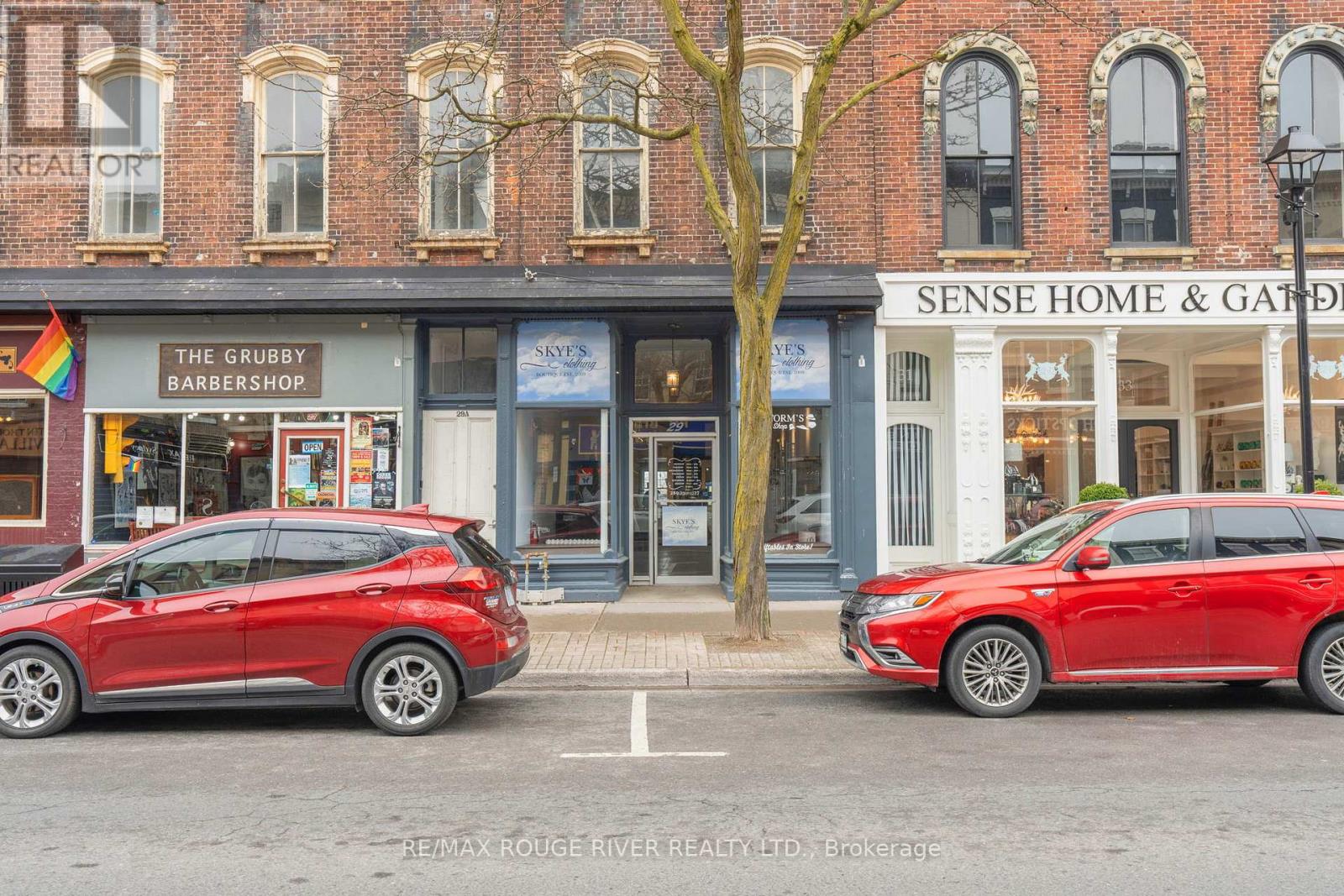 Two red cars are parked in front of a building with a sign that says "Sense Home & Garden".