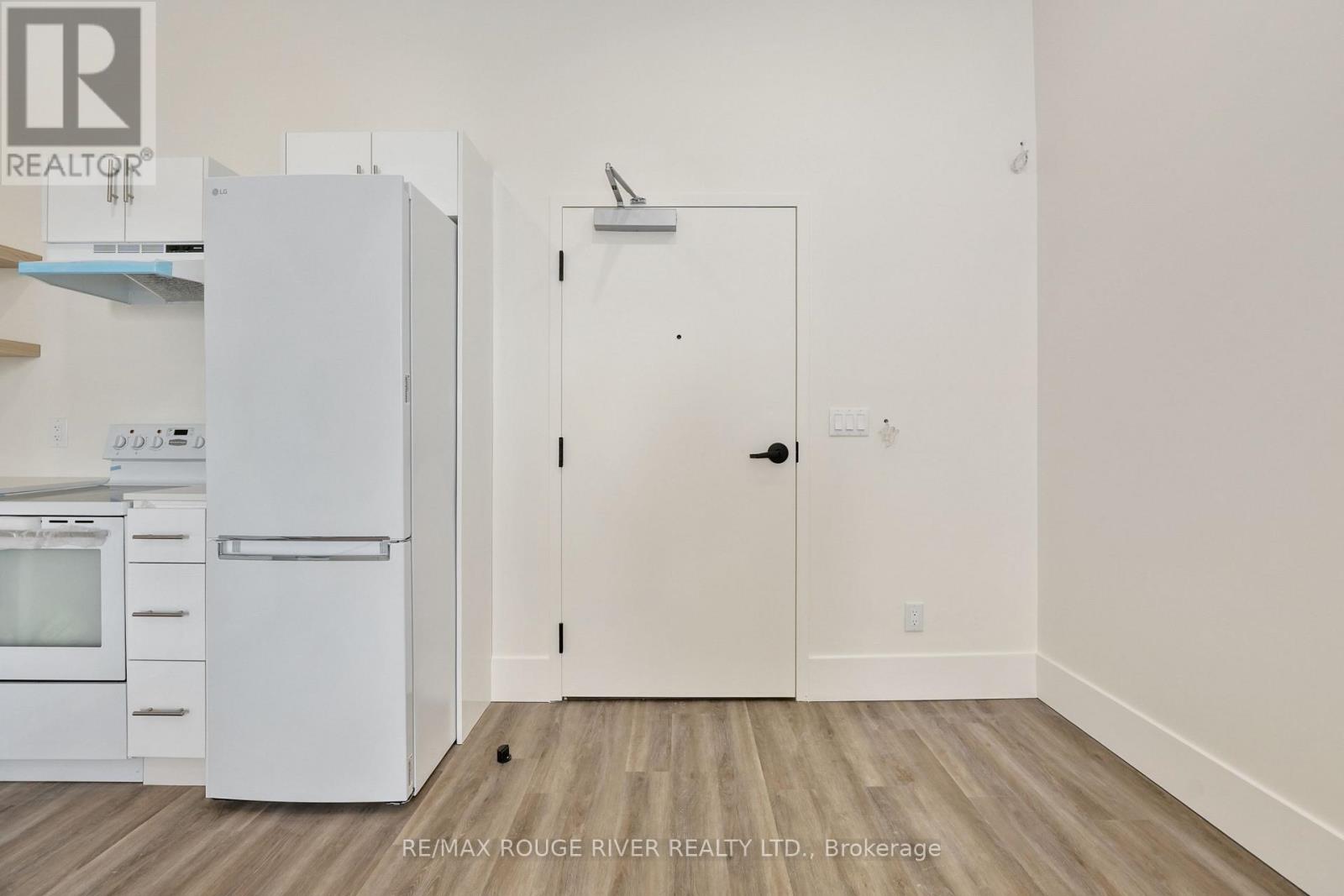 A white refrigerator and oven in a kitchen with a white door.