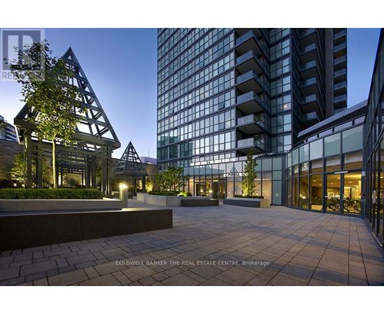 A modern building with glass windows and a tree in front of it.