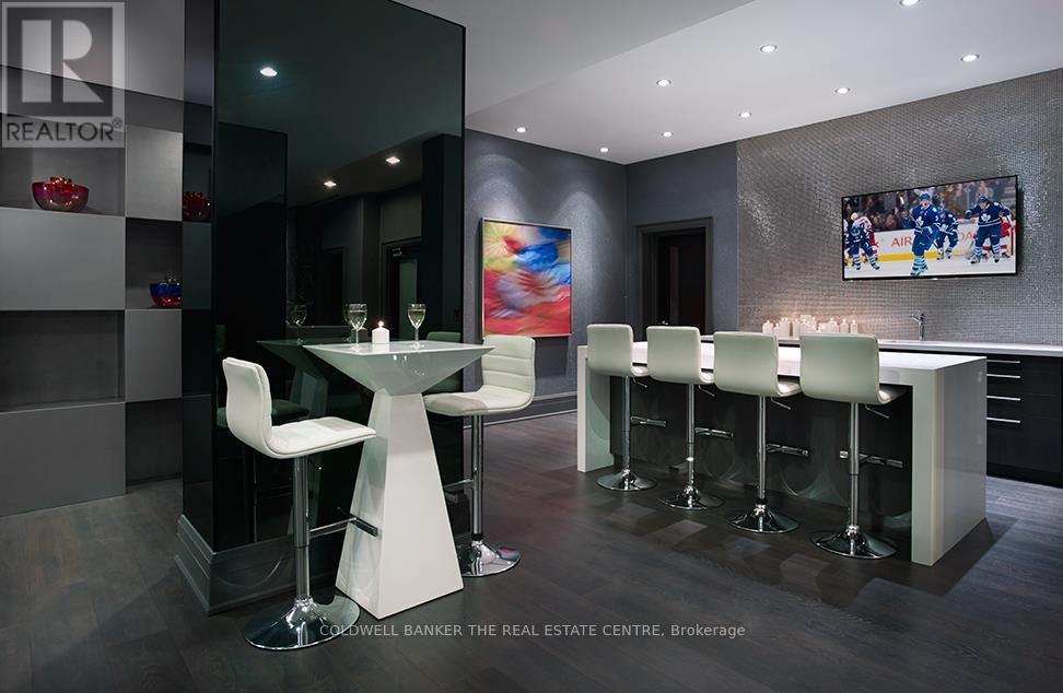 A modern bar area with a glass table and white chairs.
