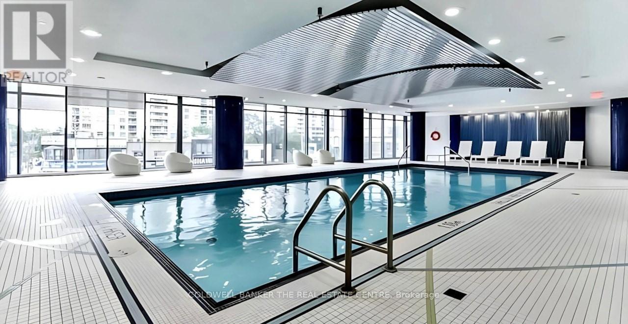 A large indoor swimming pool with a glass wall and a skylight.