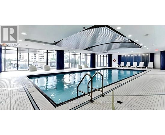 A large indoor swimming pool with a glass wall and a skylight.