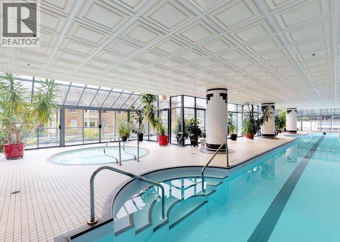 A large indoor swimming pool with a glass ceiling and a tiled floor.
