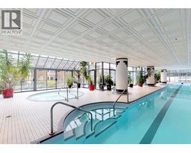 A large indoor swimming pool with a glass ceiling and a tiled floor.