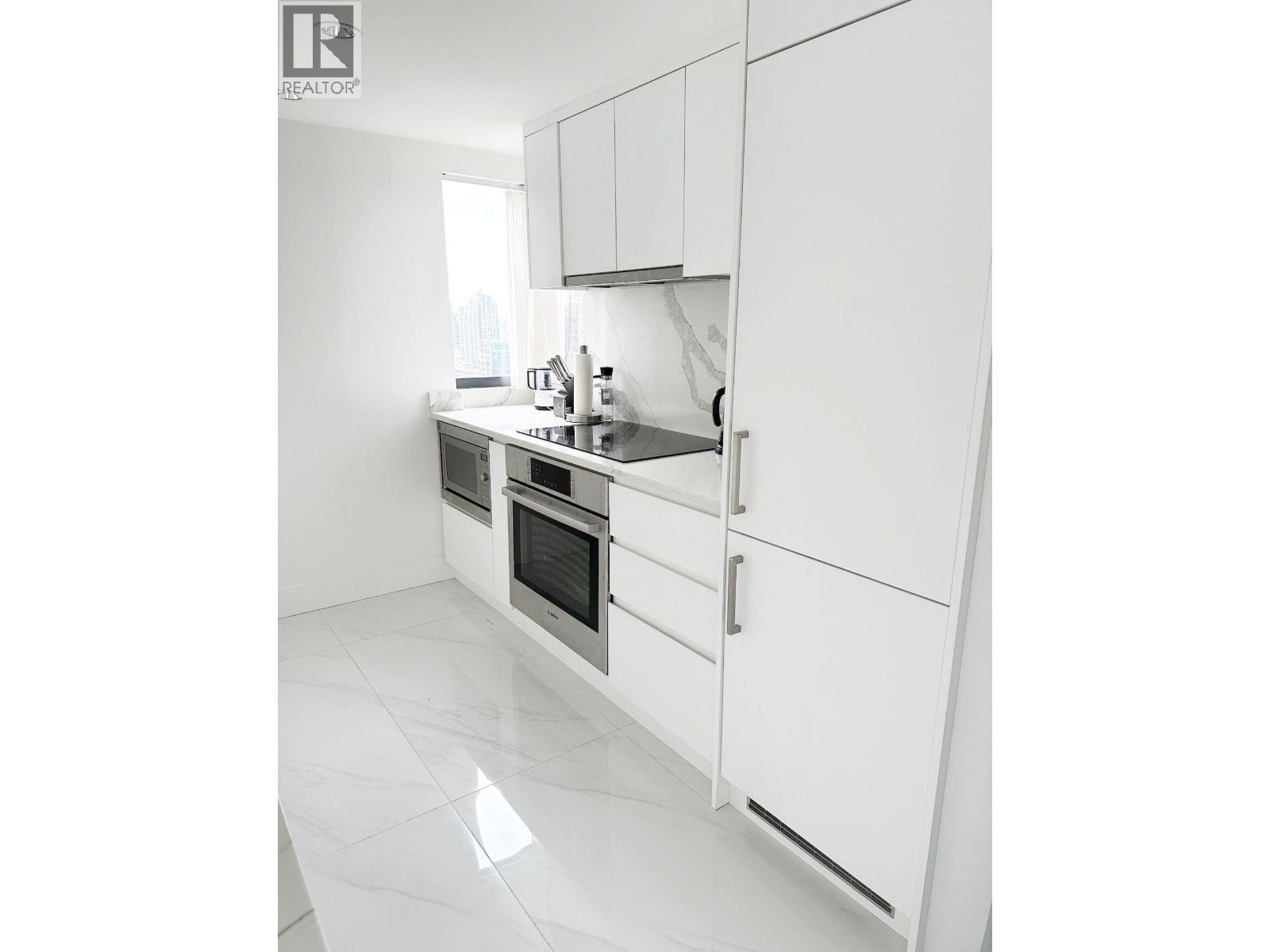 A white kitchen with a sink and a window.