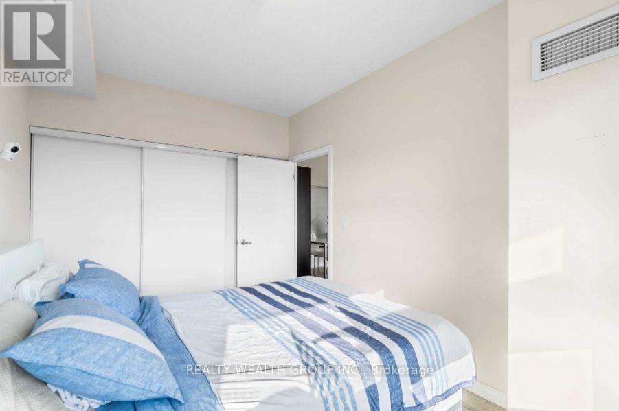 A bedroom with a bed, pillows, and a window with blinds.