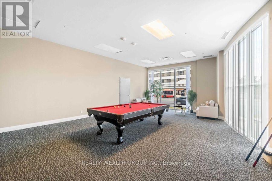 A pool table is in the middle of a room with a carpet floor.