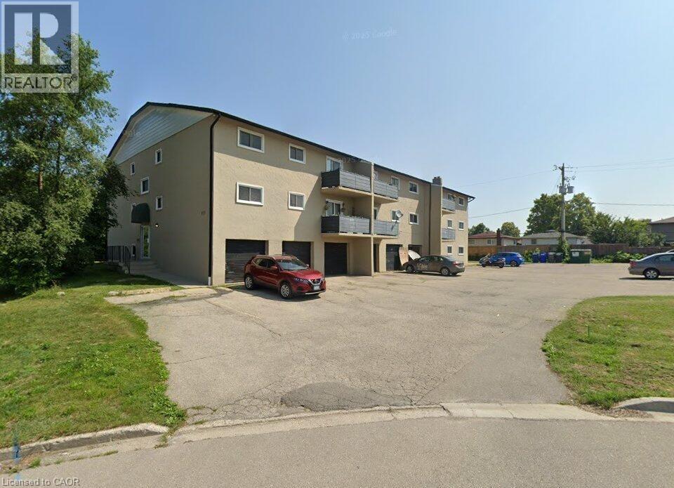A red car is parked in front of a multi-story apartment building.
