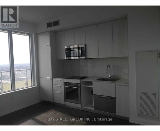 A kitchen with white cabinets and a window overlooking the city.