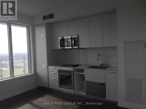 A kitchen with white cabinets and a window overlooking the city.
