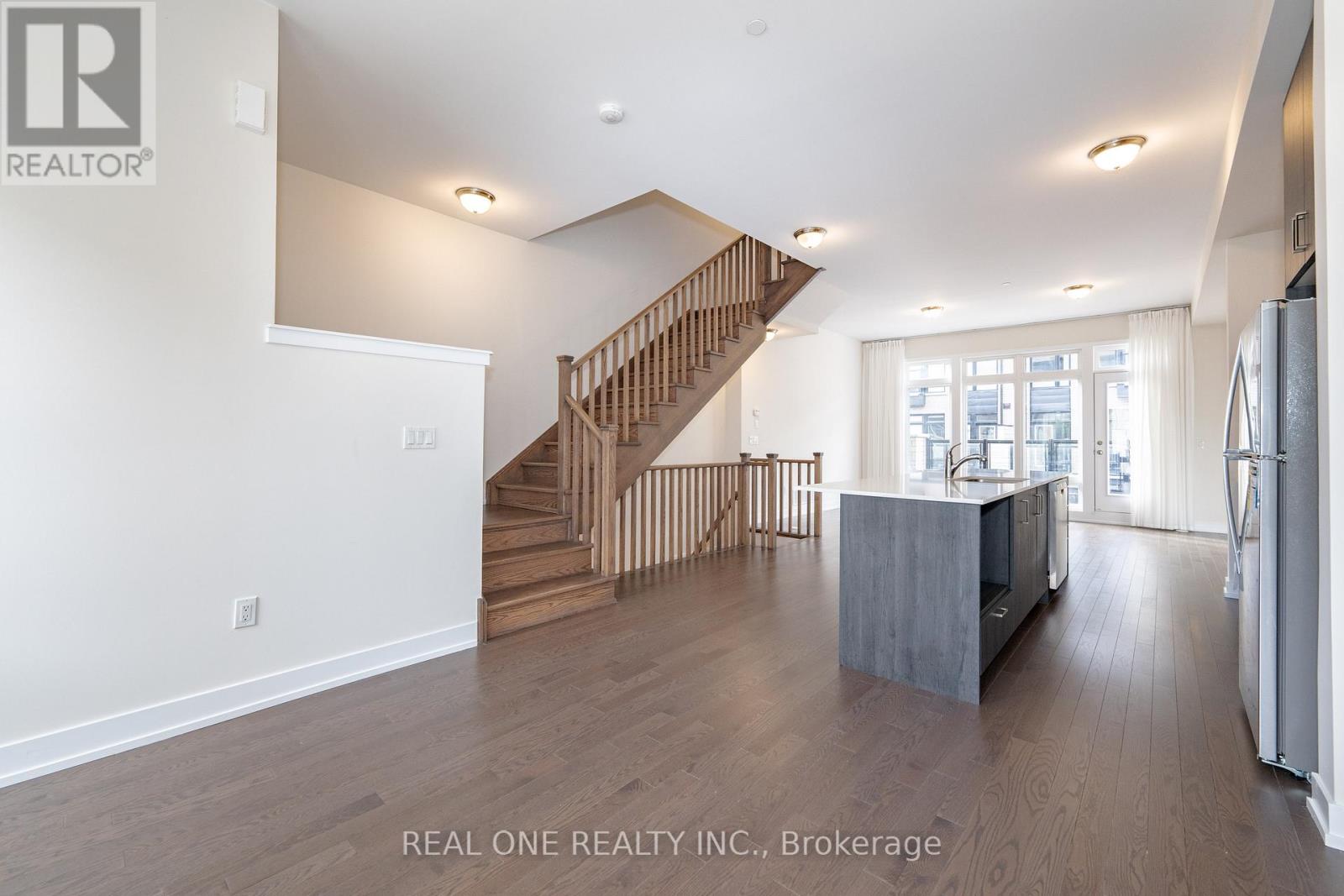 A spacious living room with a staircase leading to the upper floor.