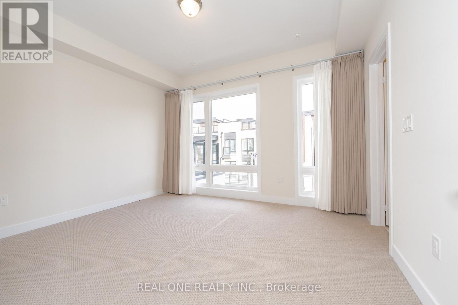 A spacious room with beige carpeting and large windows.