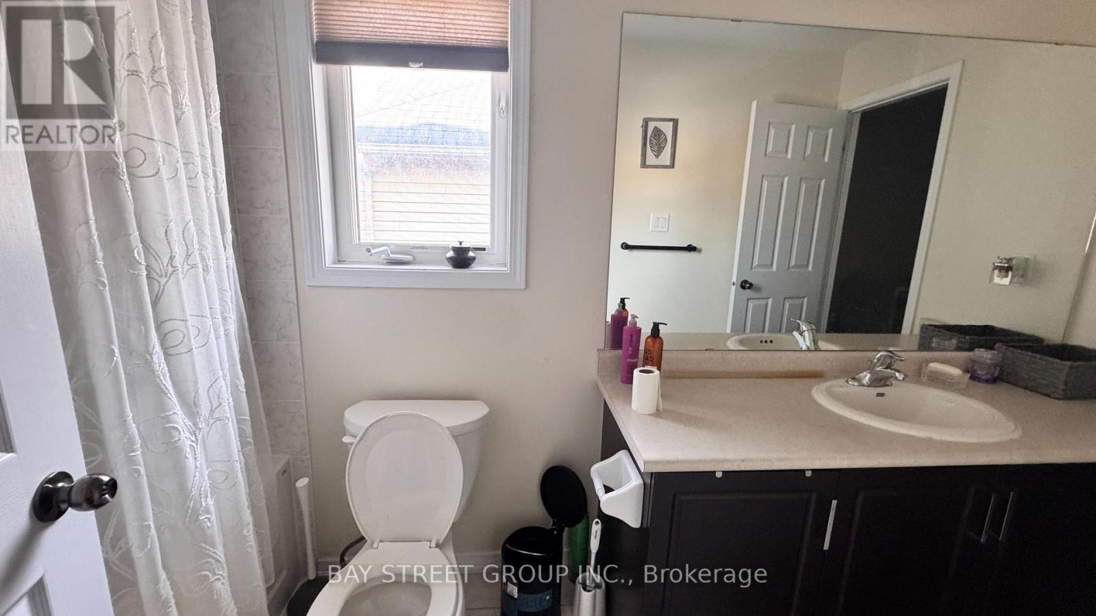 A bathroom with a toilet, sink, and mirror.