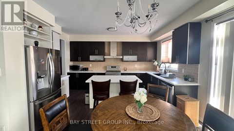 A kitchen with a refrigerator, a dining table with chairs, and a chandelier.