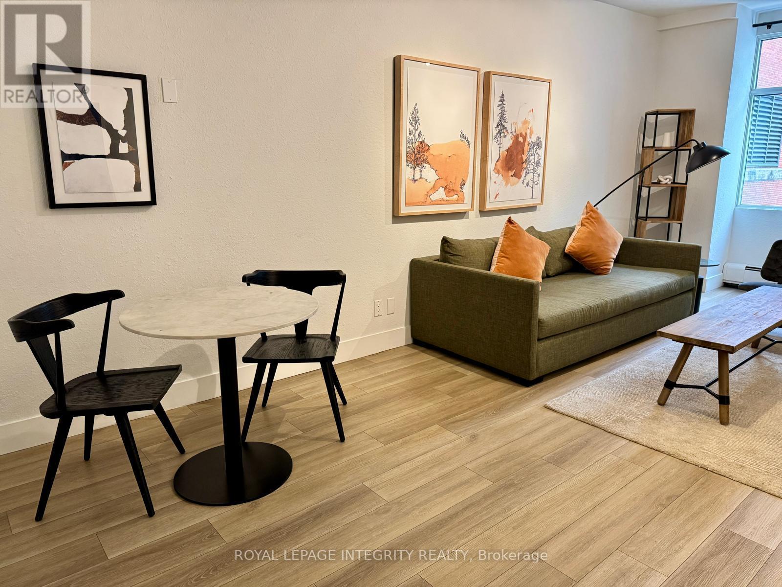 A living room with a couch, chairs, and a table.