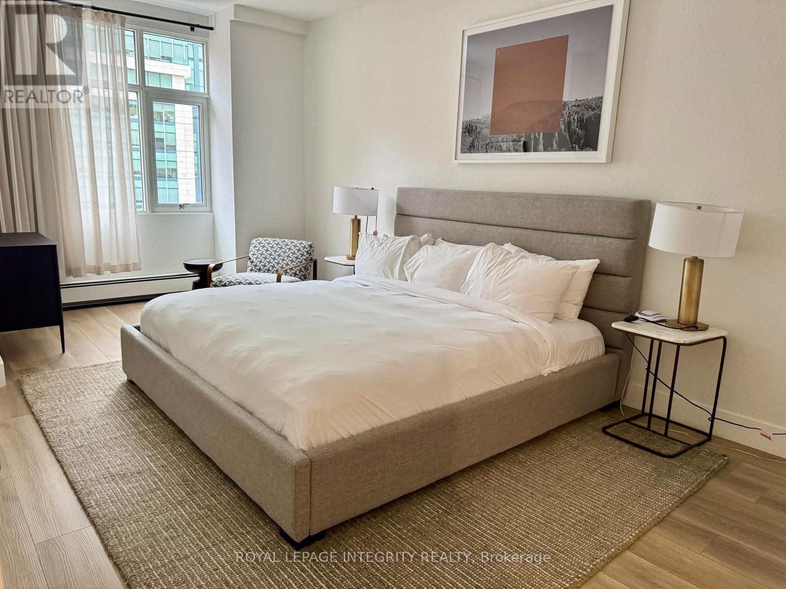 A bedroom with a large bed and a painting on the wall.