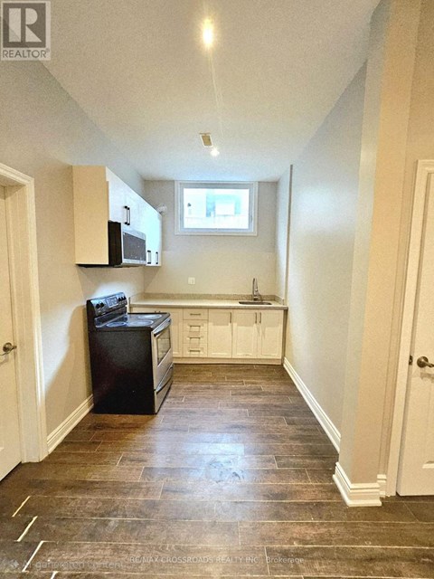 A kitchen with a black refrigerator, microwave, and oven.
