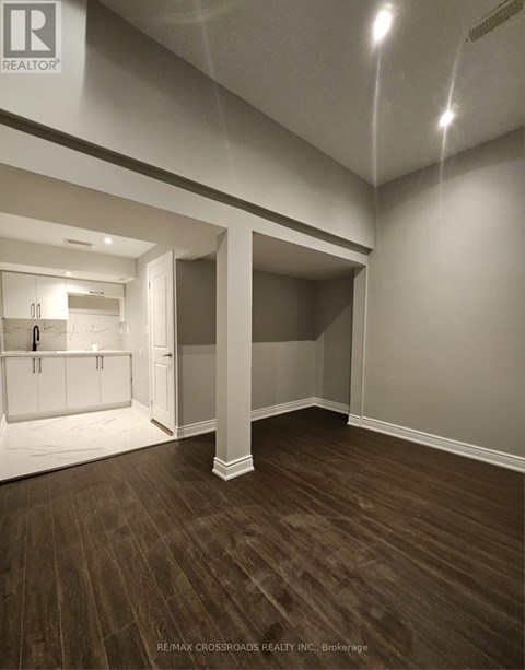 A spacious room with wood flooring and white walls.