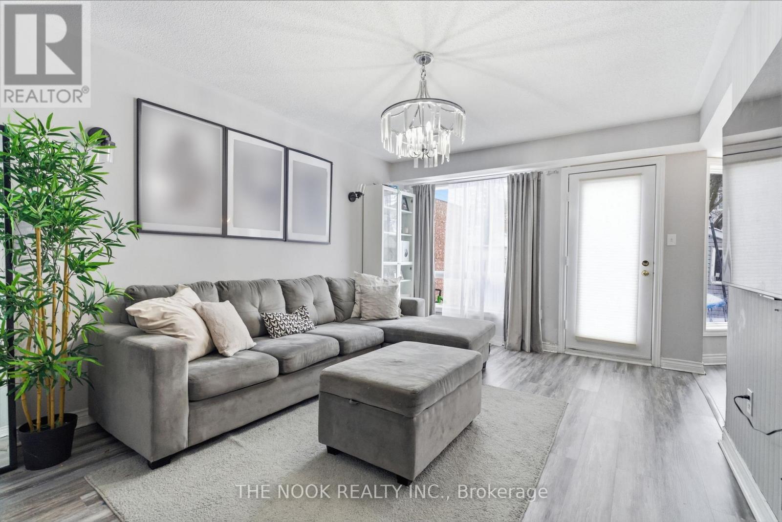 A living room with a grey couch and a chandelier.