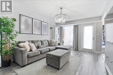 A living room with a grey couch and a chandelier.