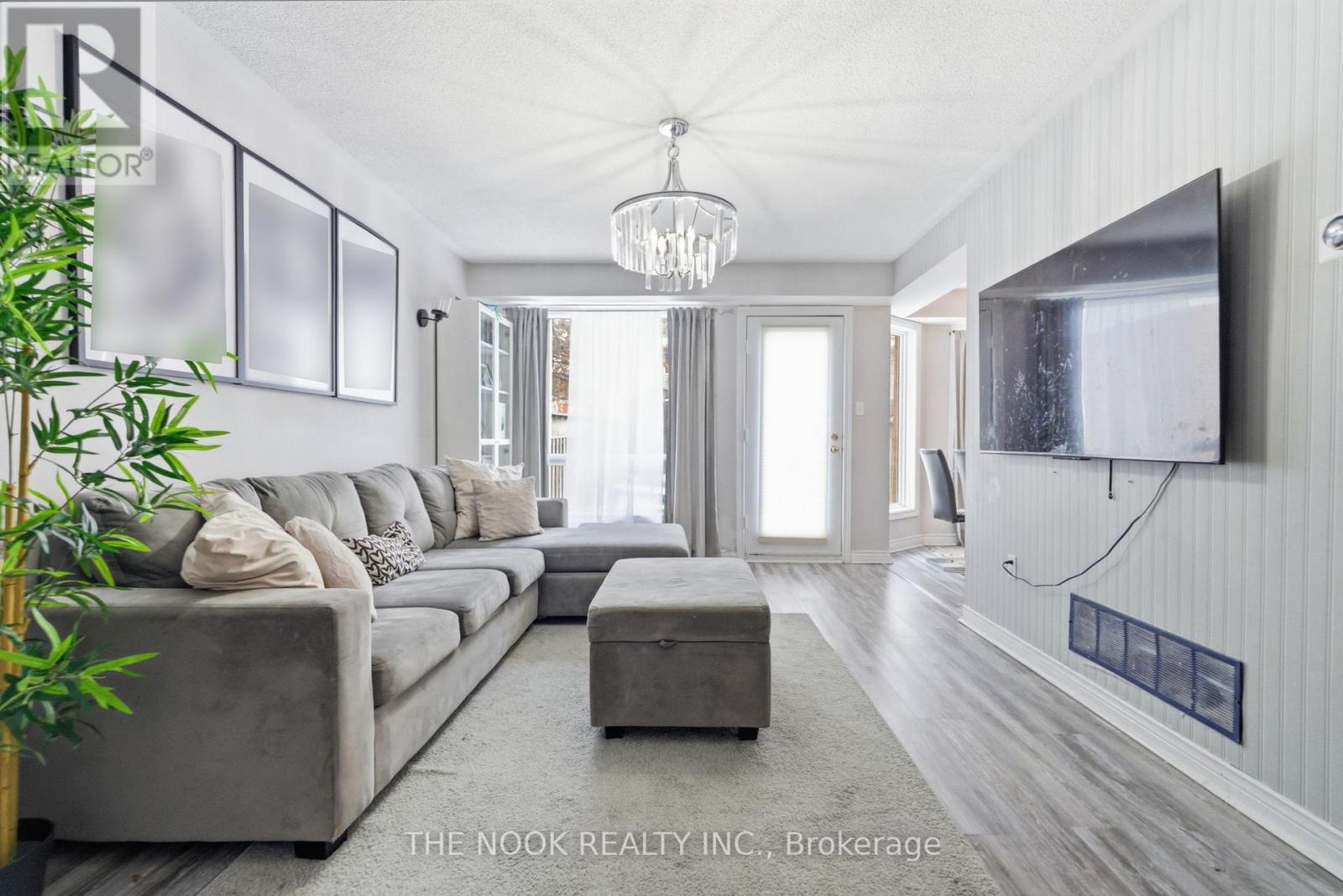 A living room with a grey couch and a flat screen TV mounted on the wall.