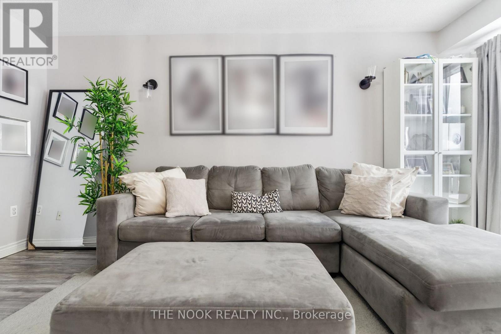 A living room with a grey couch and a green plant.