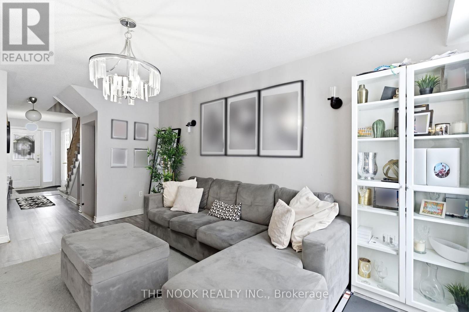A living room with a grey couch and a chandelier.